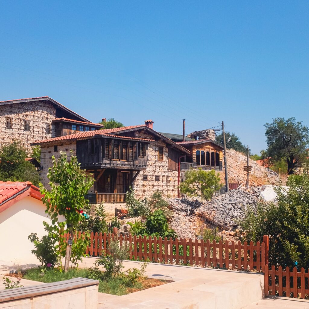 Charming stone houses surrounded by greenery under a clear blue sky.